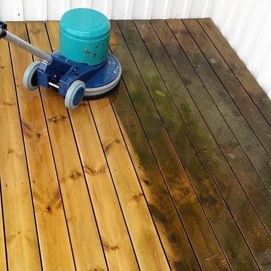 Uteplats i trä som rengörs med maskin, den vänstra delen är ren och den högra har kvar grön beläggning